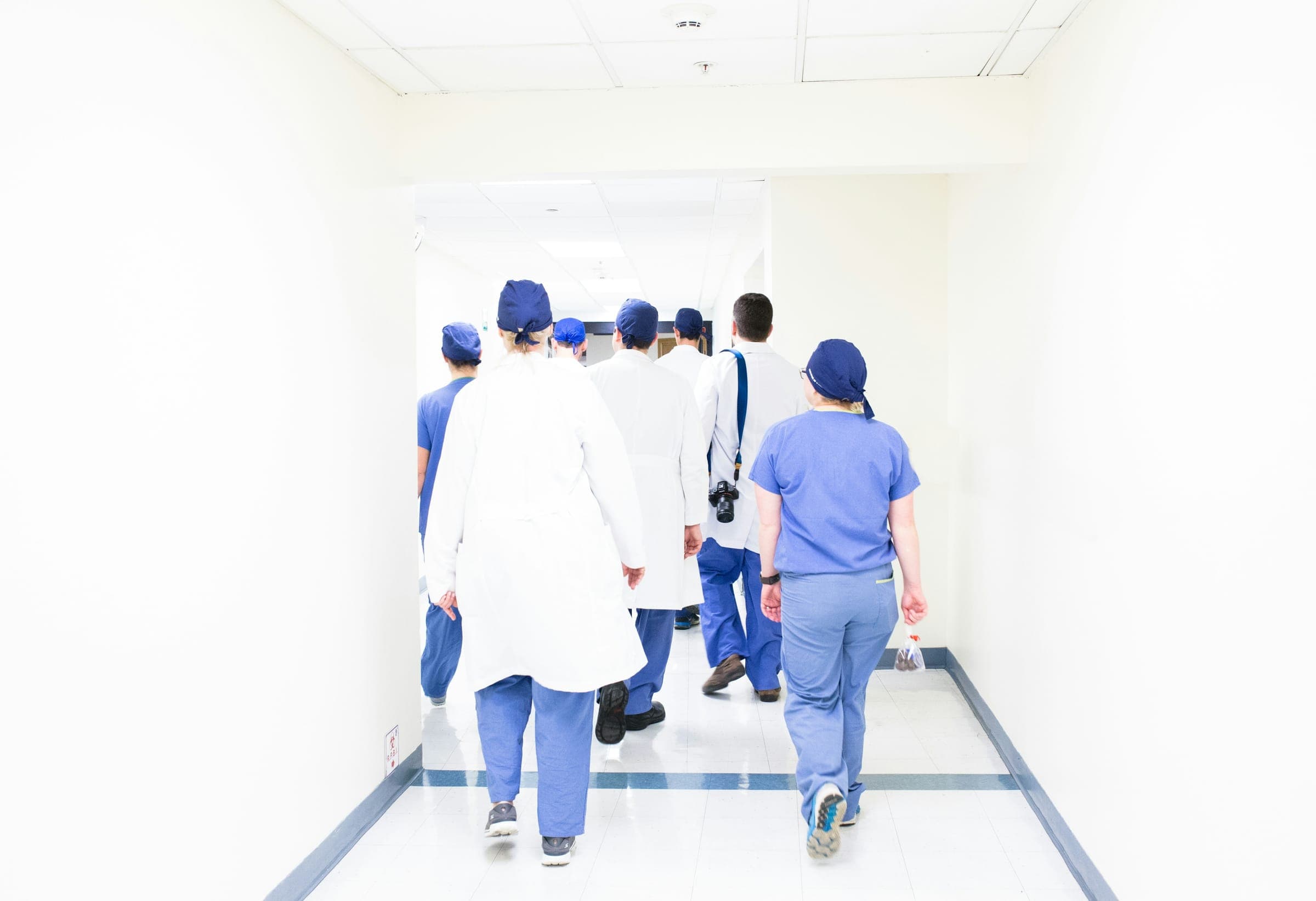 A care team in scrubs and white coats walking down a hospital corridor together